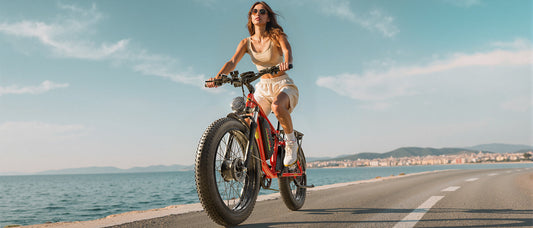 A girl rides an electric bicycle on a road by the sea.