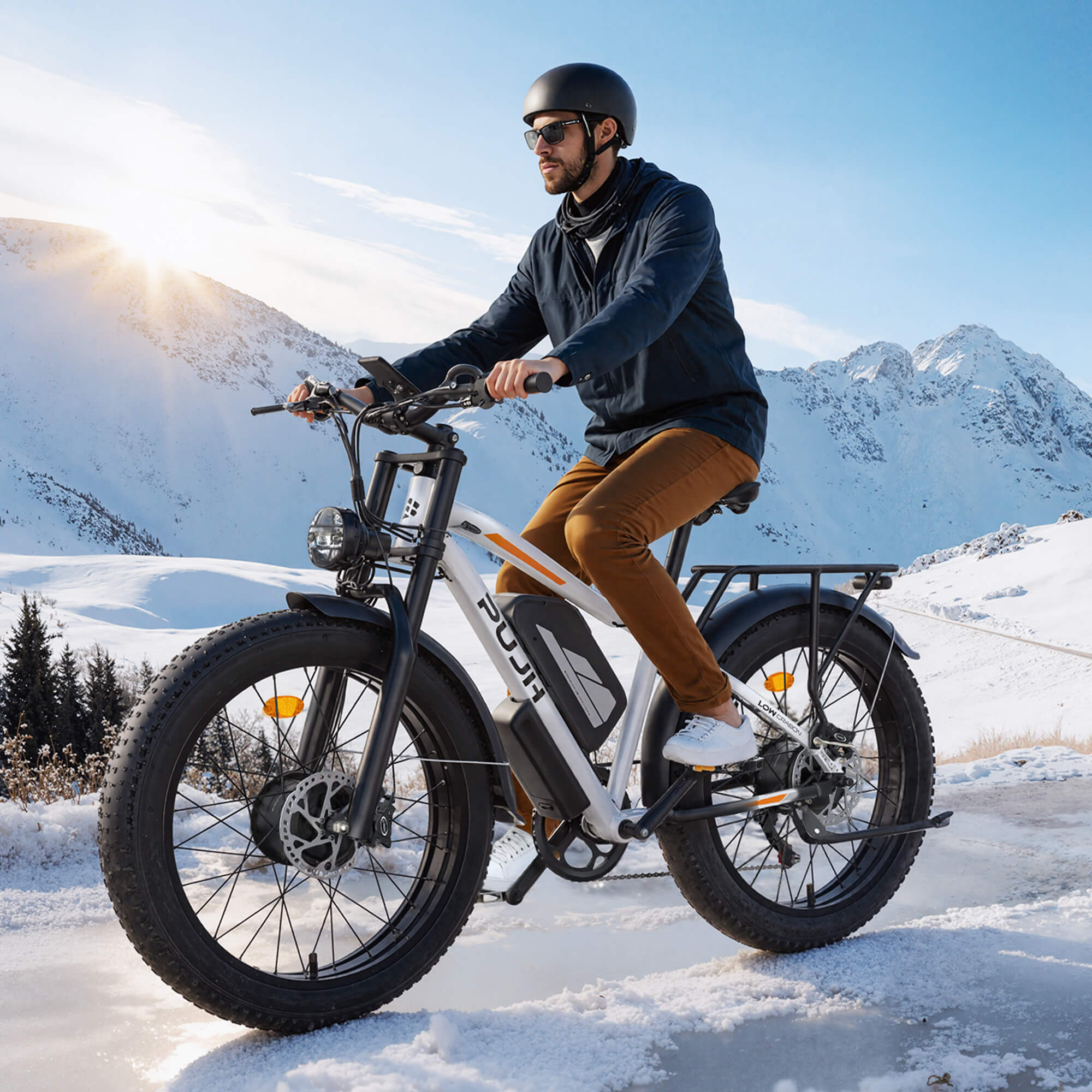 A man riding an electric bike on a snowy trail with mountains in the background