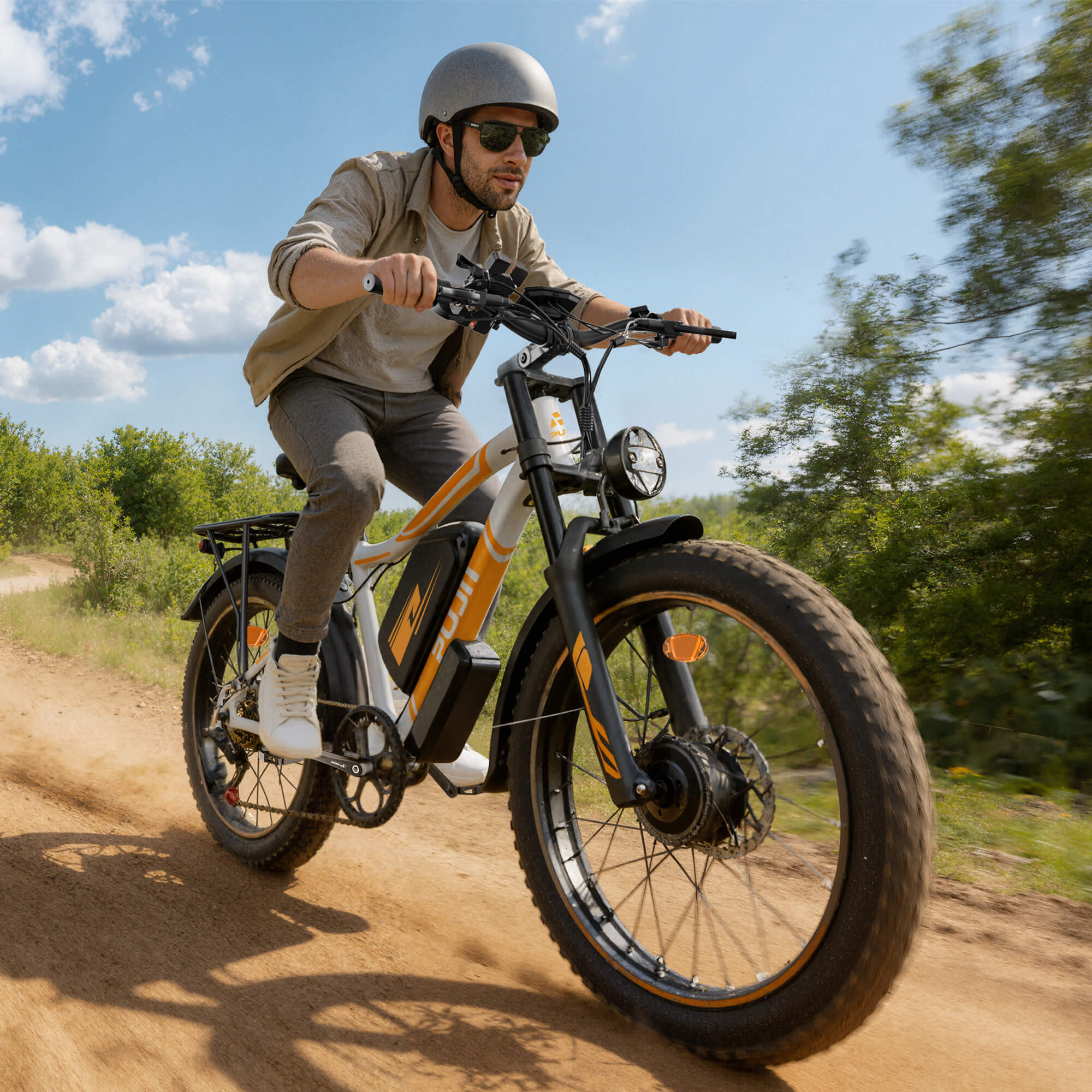 Man riding an electric bike on a dirt path with trees and blue sky in the background