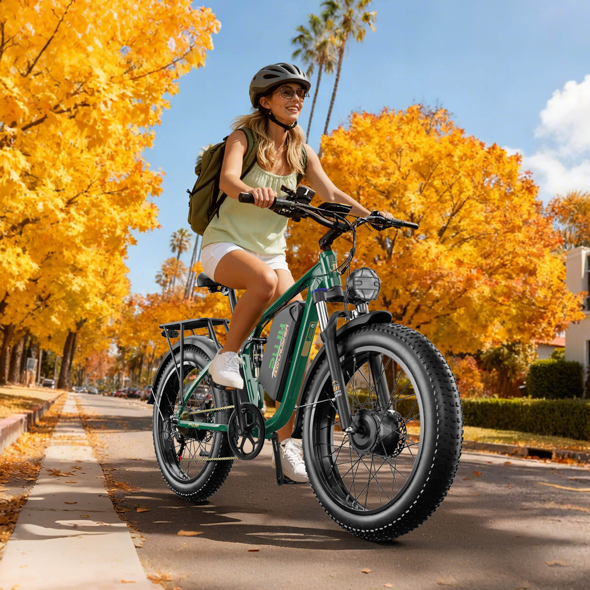 Woman riding a green electric bike on a street with autumn foliage.
